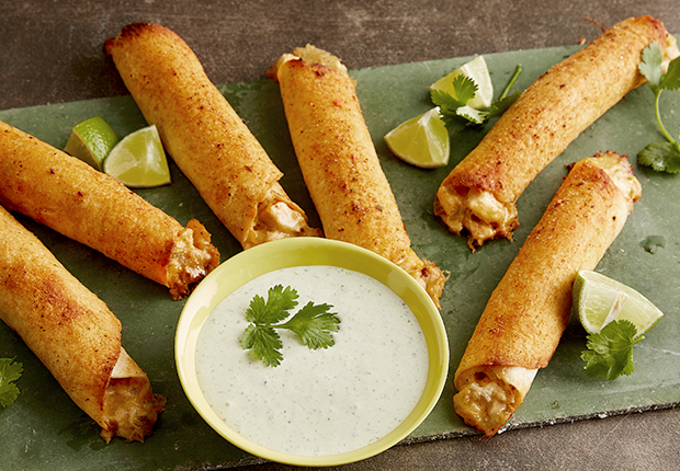 Baked Cheesy Chicken Fautas on a serving mat with a dipping sauce