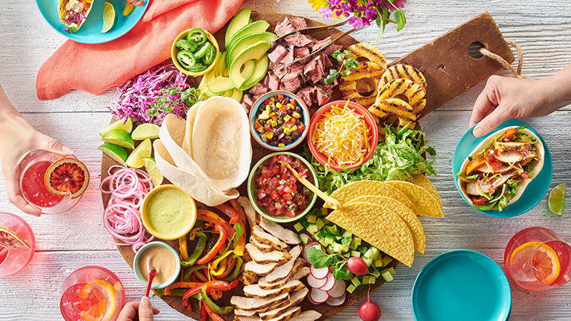 Tex-Mex style Charcuterie Board that includes taco shells, grilled chicken breast, avocado, grilled peppers and shredded cheese