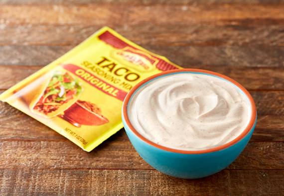Old El Paso original taco seasoning, front of package, next to a small bowl of sour cream