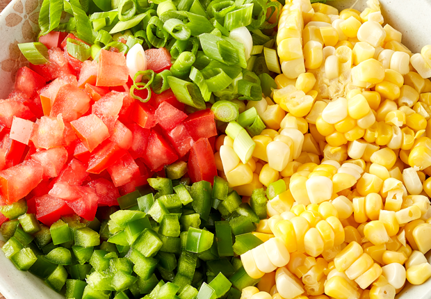 Corn, diced tomatoes, sliced green onion and minced jalapeno in a bowl