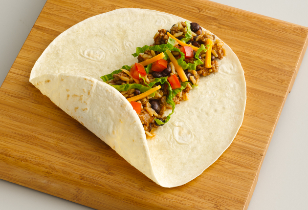 Burrito ingredients at the center on a burrito tortilla with the bottom third of the tortilla folded up