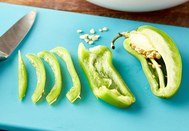 Sliced jalapeño on a cutting board with seeds on the side